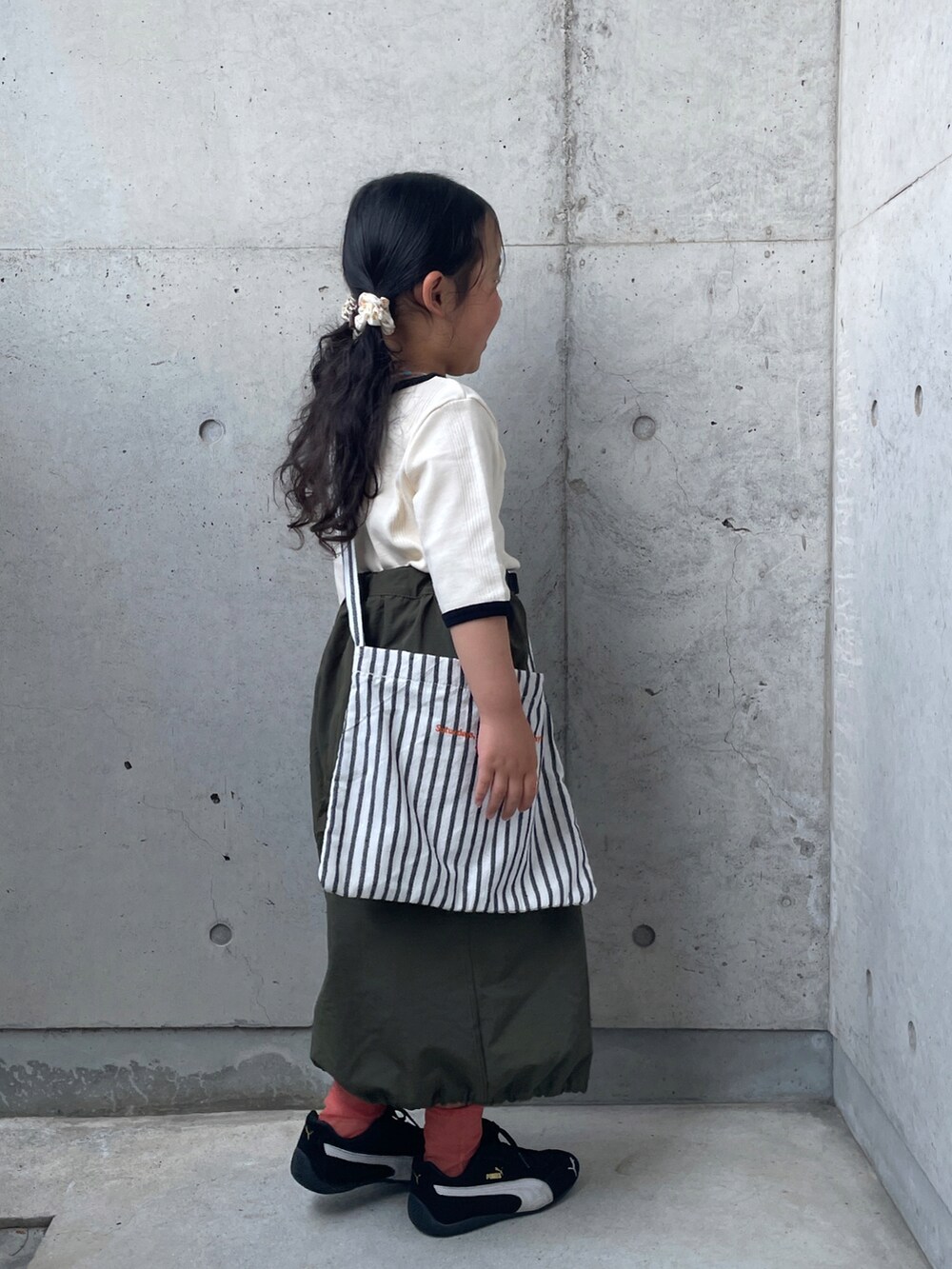 ホワイト系のTシャツ/カットソー、グリーン系のスカート、ブラック系のスニーカーを着用したキッズの春コーディネートの2枚目の写真