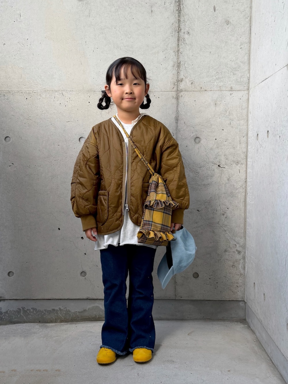 ブルー系のデニムパンツ、グレー系のワンピース、イエロー系のバックパック/リュックを着用したキッズの秋コーディネートの3枚目の写真