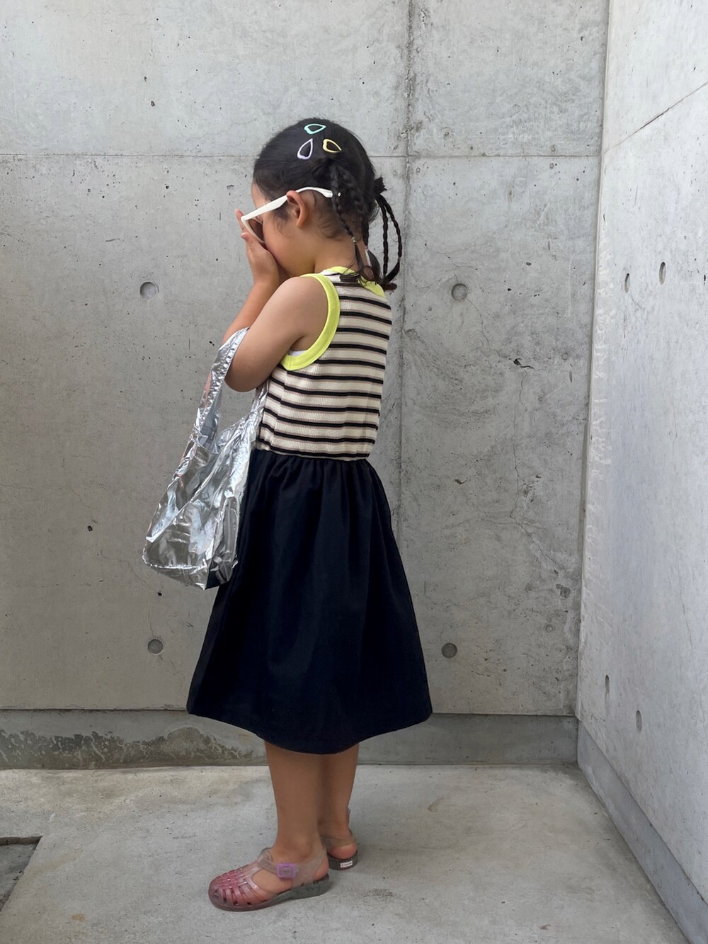 ホワイト系のサンダル、ブラック系のワンピース、シルバー系のハンドバッグを着用したキッズの夏コーディネートの2枚目の写真