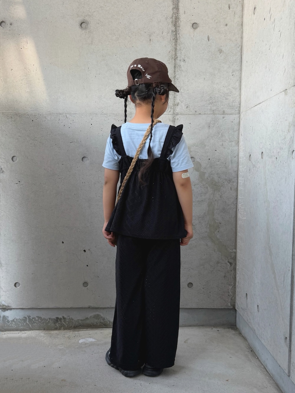 ブラック系のセットアップ、ベージュ系のショルダーバッグ、ブラック系のサンダルを着用したキッズの夏コーディネートの3枚目の写真