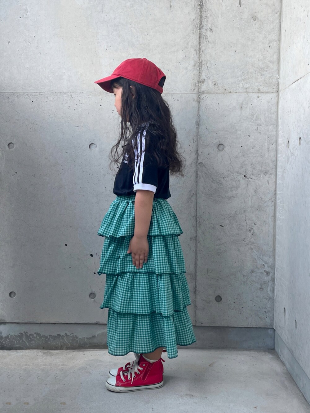 ブラック系のTシャツ/カットソー、レッド系のスニーカー、グリーン系のスカートを着用したキッズの秋コーディネートの2枚目の写真