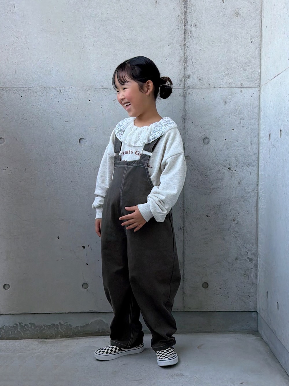グレー系のサロペット/オーバーオール、ベージュ系のスウェット、ブラック系のスリッポンを着用したキッズの秋コーディネートの5枚目の写真