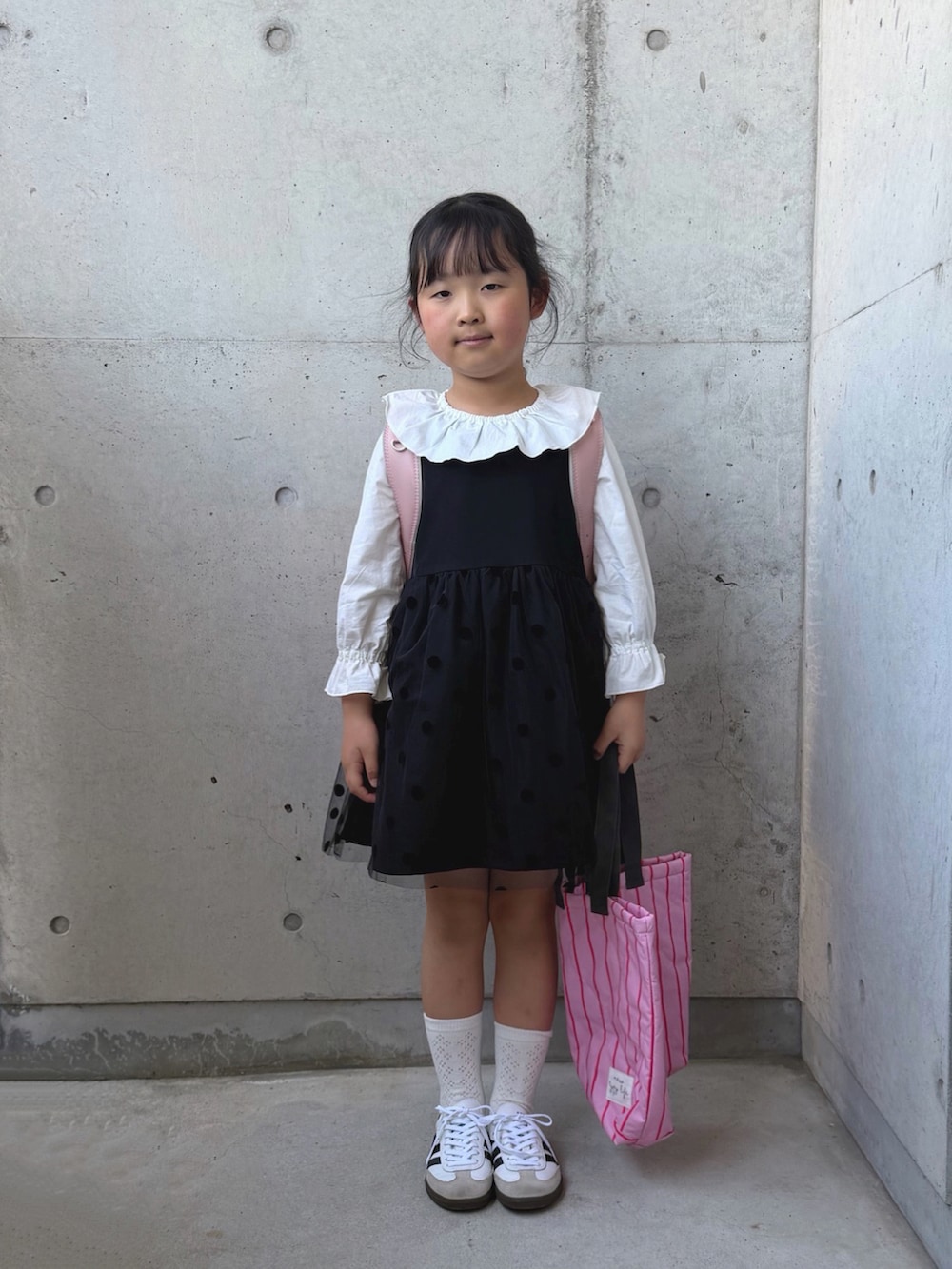 ホワイト系のシャツ/ブラウス、ブラック系のワンピース、ピンク系のトートバッグを着用したキッズの春コーディネートの2枚目の写真