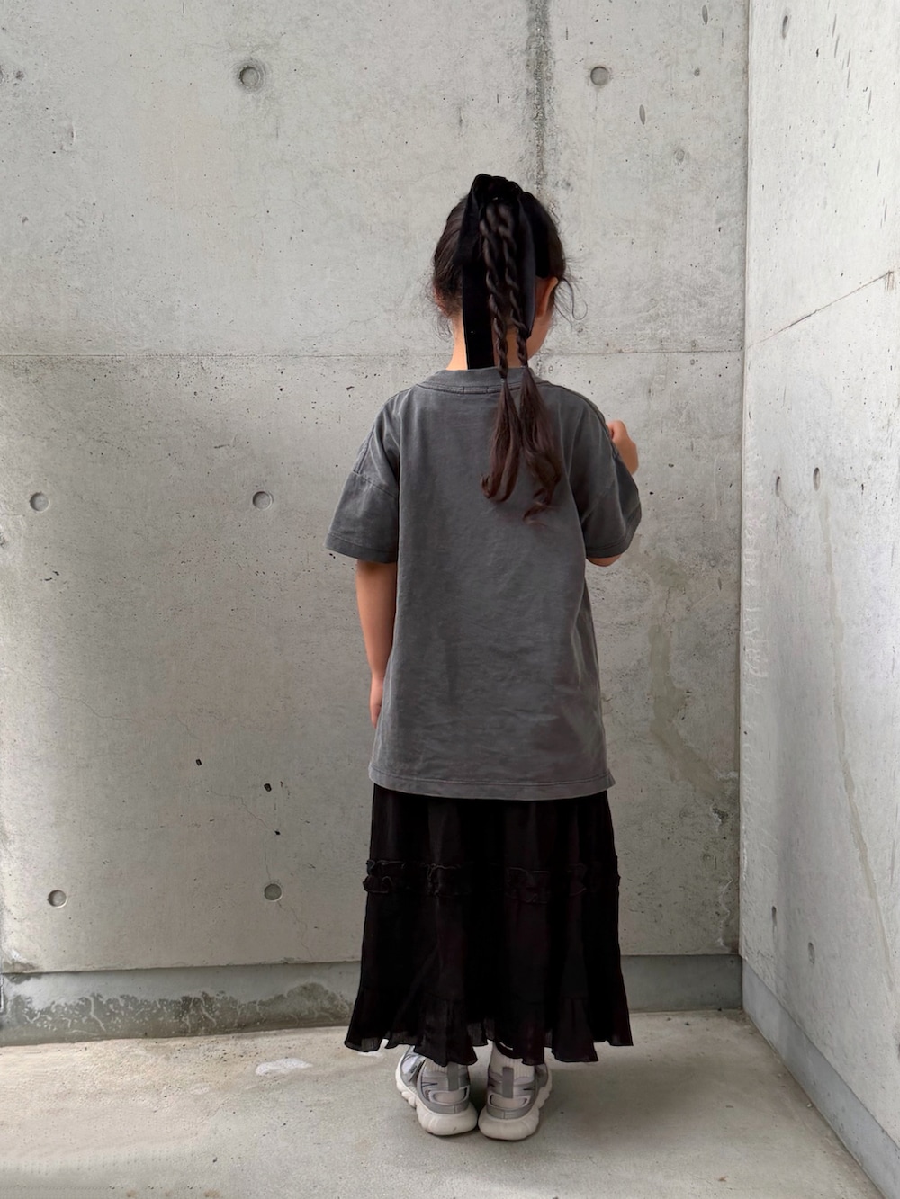 ブラック系のスカート、シルバー系のスニーカー、グレー系のTシャツ/カットソーを着用したキッズの夏コーディネートの2枚目の写真