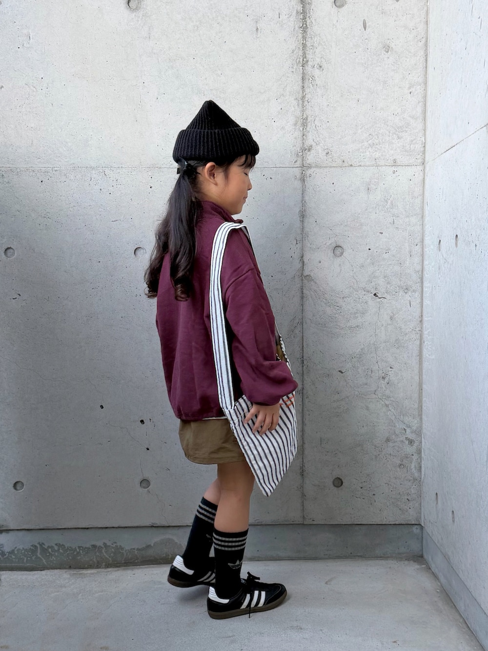 ブラック系のスニーカー、グリーン系のスカート、レッド系のスウェットを着用したキッズの秋コーディネートの5枚目の写真