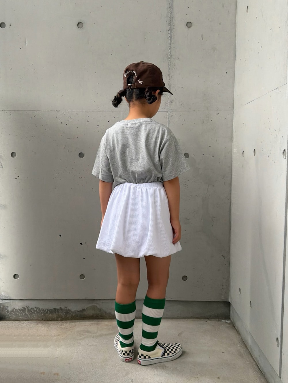 ブラック系のスリッポン、グレー系のTシャツ/カットソー、ホワイト系のスカートを着用したキッズの夏コーディネートの2枚目の写真