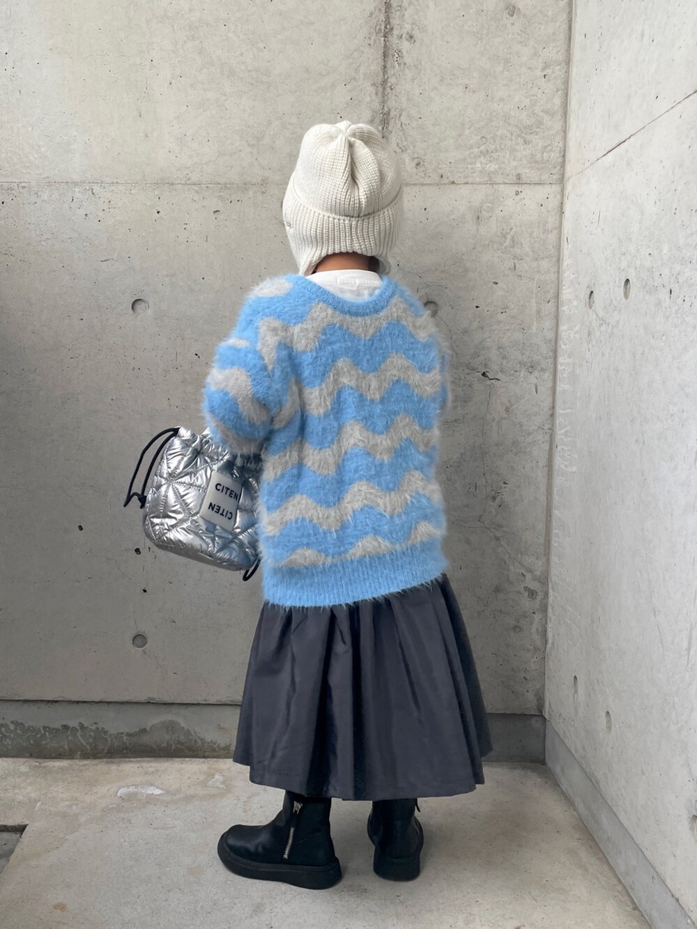 ブルー系のニット/セーター、グレー系のワンピース、シルバー系のトートバッグを着用したキッズの秋コーディネートの3枚目の写真