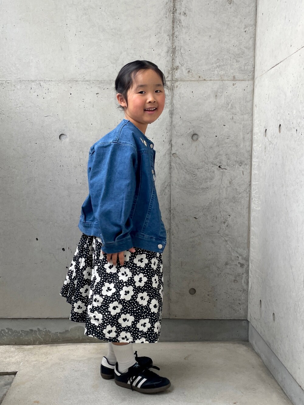 ブラック系のスニーカー、ブラック系のワンピース、ブルー系のデニムジャケットを着用したキッズの春コーディネートの5枚目の写真