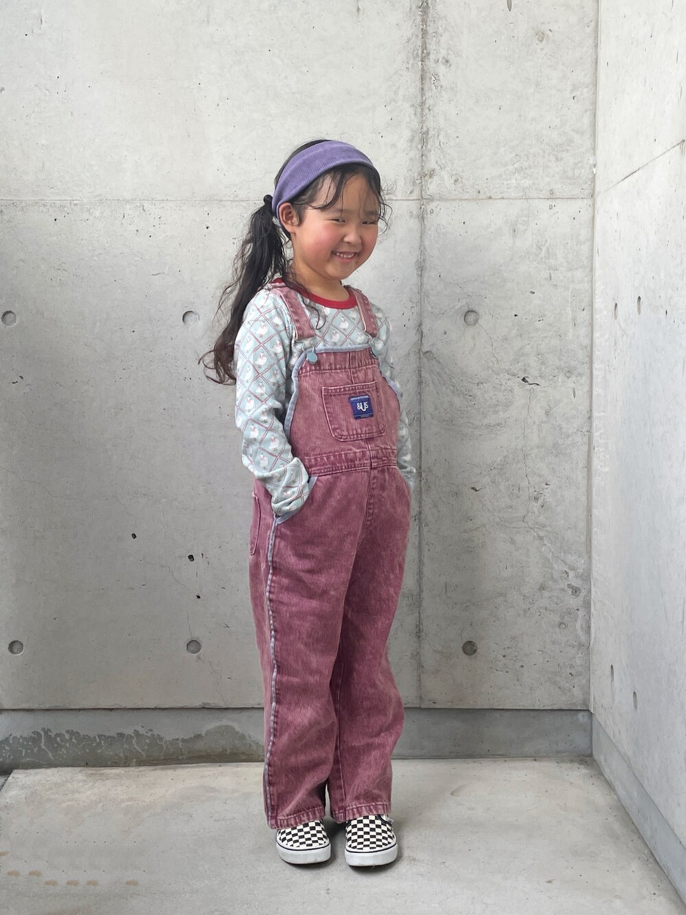 ブラック系のスリッポン、ブルー系のトップス、レッド系のサロペット/オーバーオールを着用したキッズの秋コーディネートの3枚目の写真