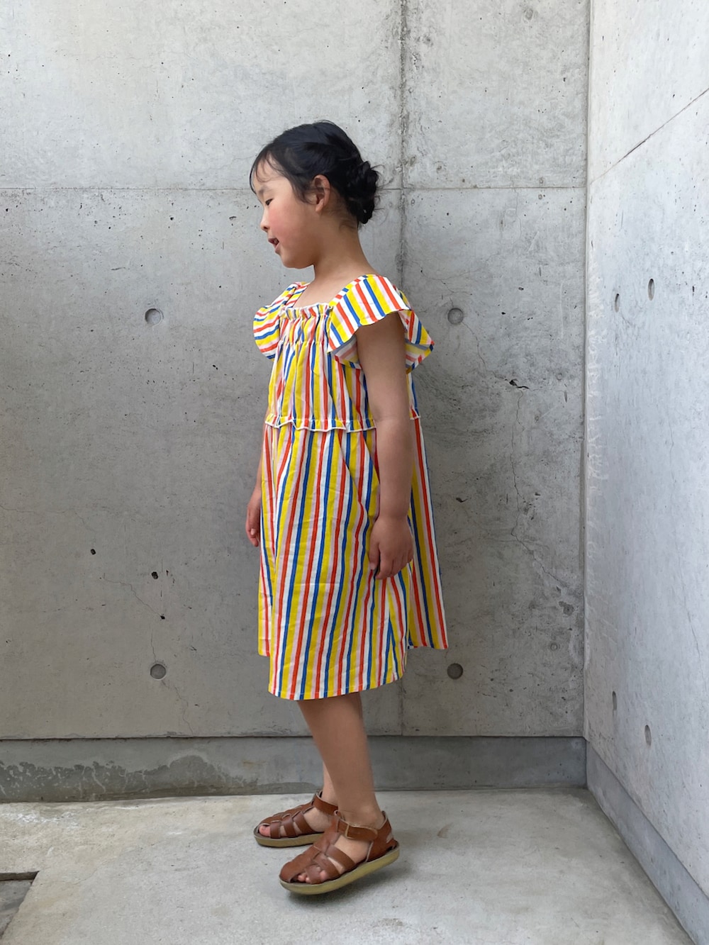 ベージュ系のサンダル、イエロー系のワンピースを着用したキッズの春コーディネートの2枚目の写真