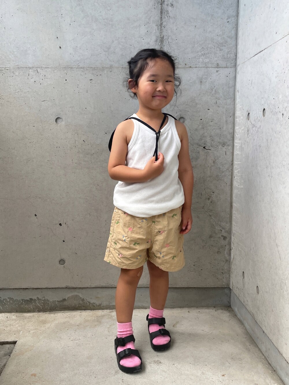 ホワイト系のタンクトップ、ベージュ系のパンツ、ブラック系のサンダルを着用したキッズの夏コーディネートの5枚目の写真
