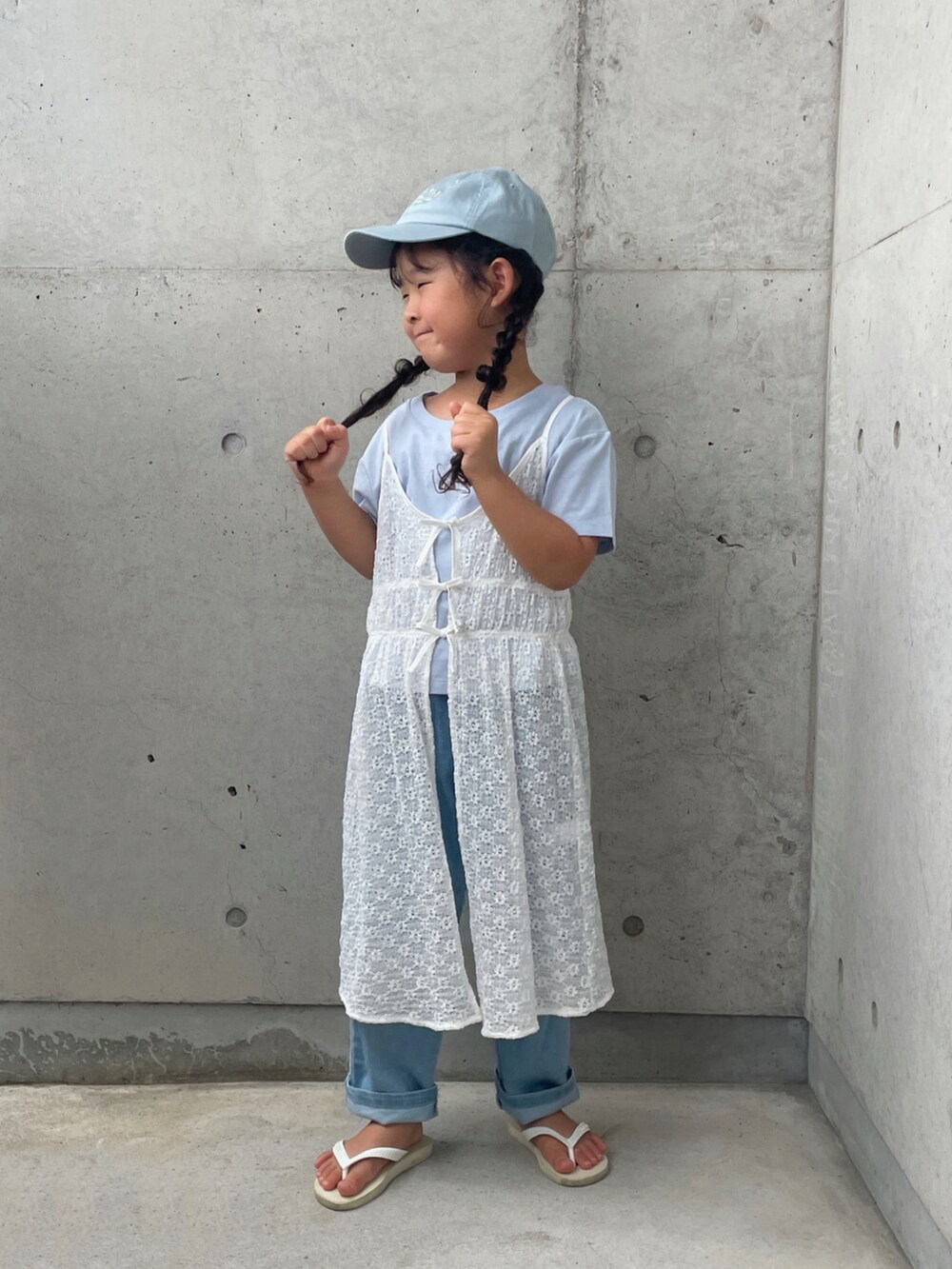 ブルー系のデニムパンツ、ホワイト系のサンダル、ホワイト系のワンピース/ドレスを着用したキッズの夏コーディネートの2枚目の写真