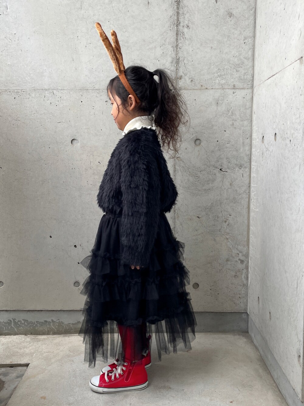 ブラック系のスカート、ホワイト系のニット/セーター、レッド系のスニーカーを着用したキッズの冬コーディネートの2枚目の写真