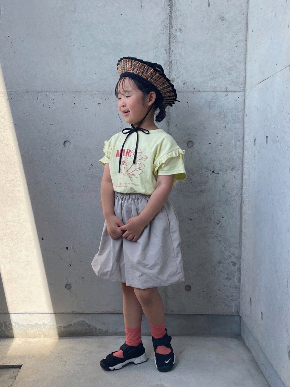 ブラック系のスニーカー、ベージュ系のTシャツ/カットソー、ベージュ系のスカートを着用したキッズの夏コーディネートの2枚目の写真
