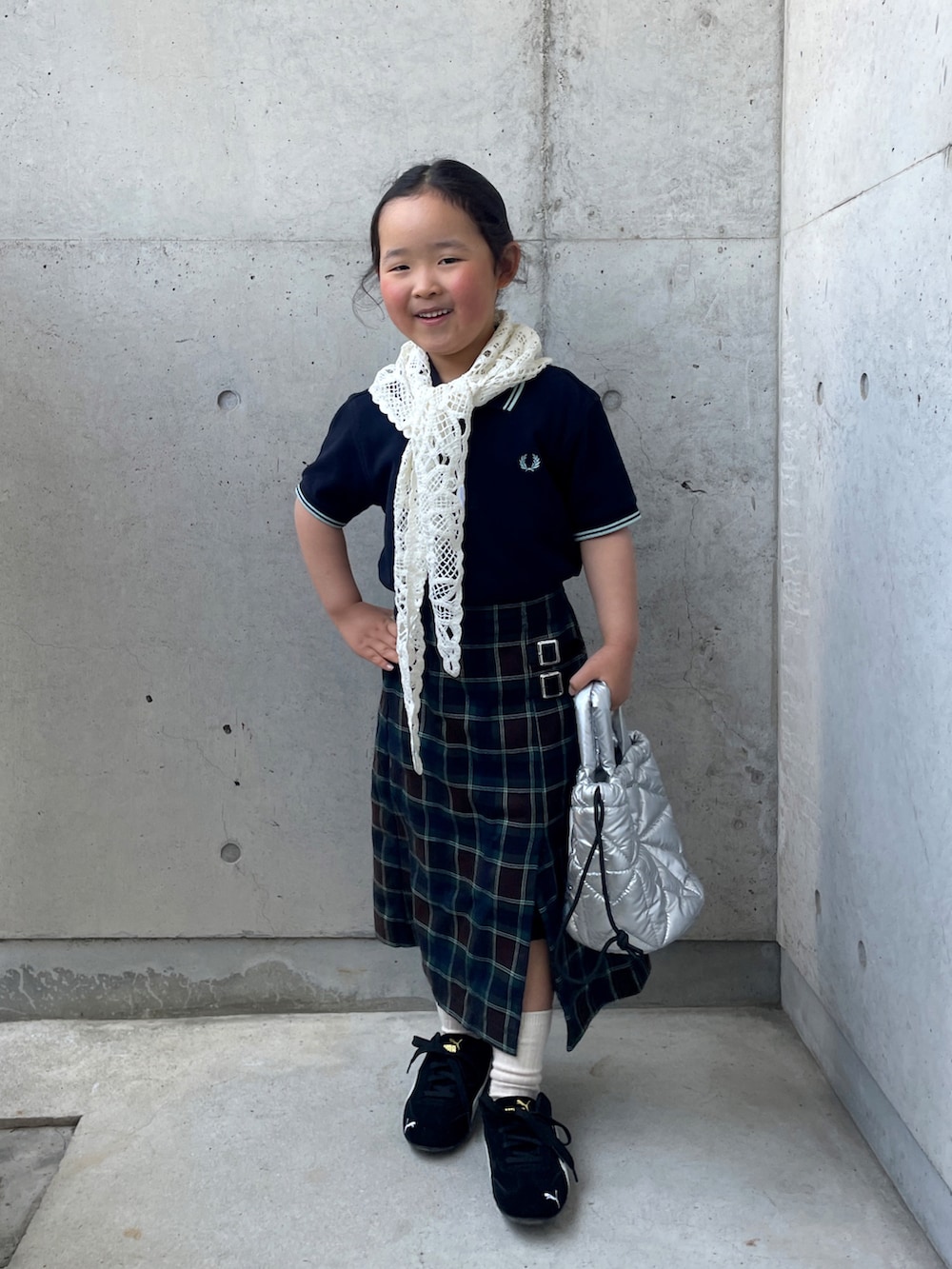 ブラウン系のスカート、ブルー系のポロシャツ、ブラック系のスニーカーを着用したキッズの春コーディネートの2枚目の写真