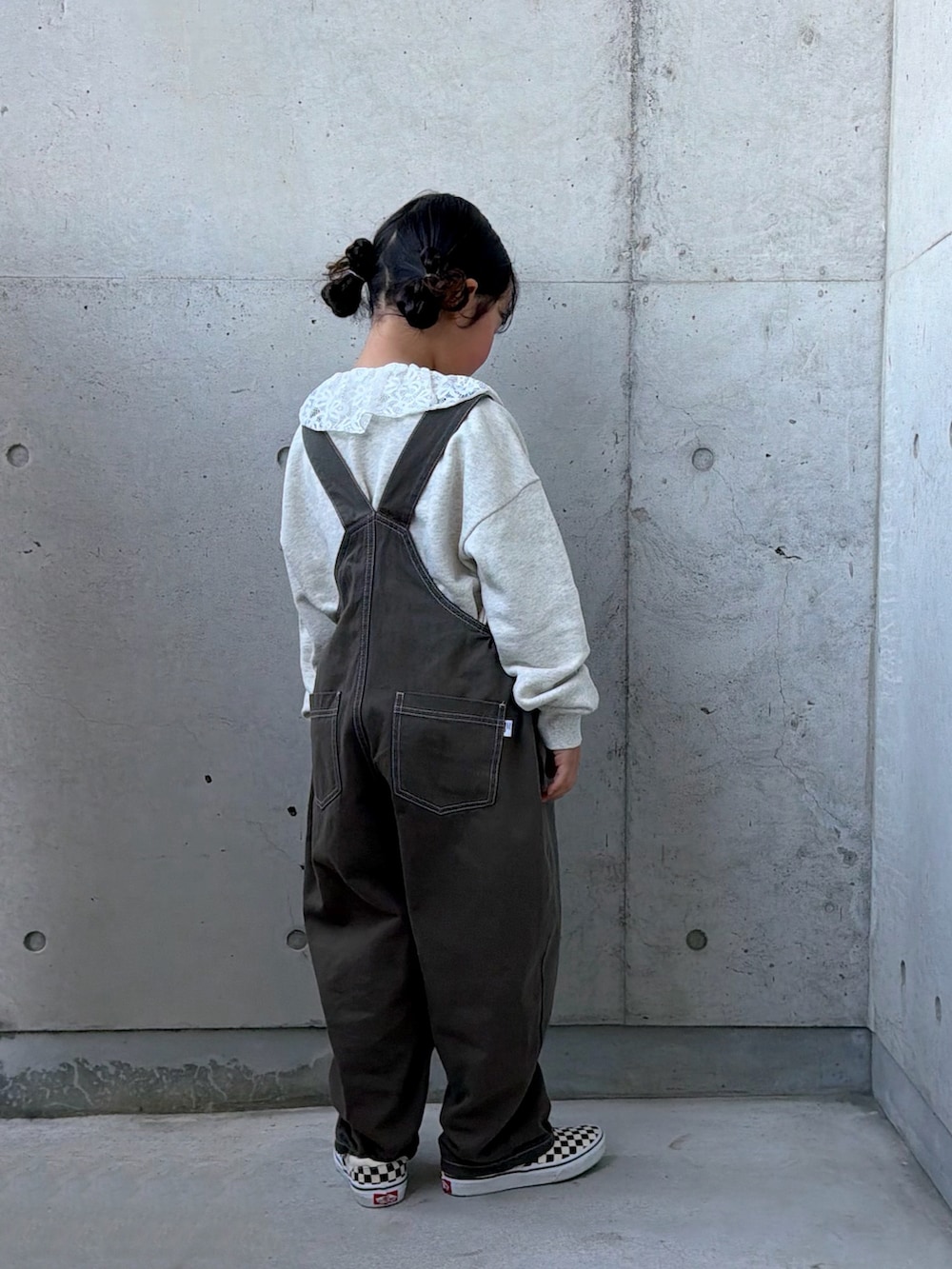 グレー系のサロペット/オーバーオール、ベージュ系のスウェット、ブラック系のスリッポンを着用したキッズの秋コーディネートの4枚目の写真