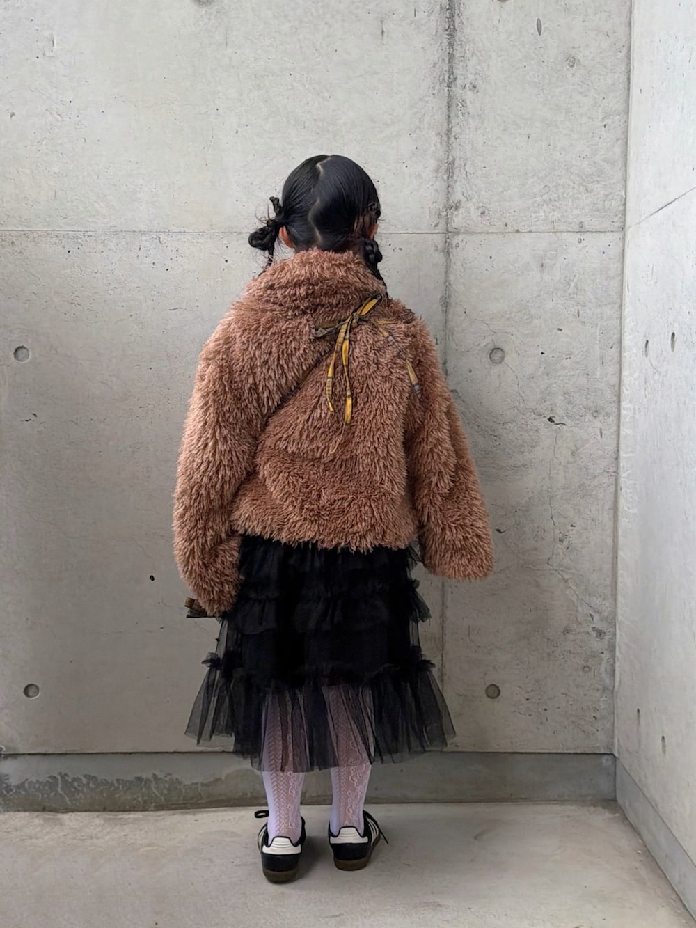 イエロー系のバックパック/リュック、ブラック系のスニーカー、レッド系のニット/セーターを着用したキッズの冬コーディネートの3枚目の写真