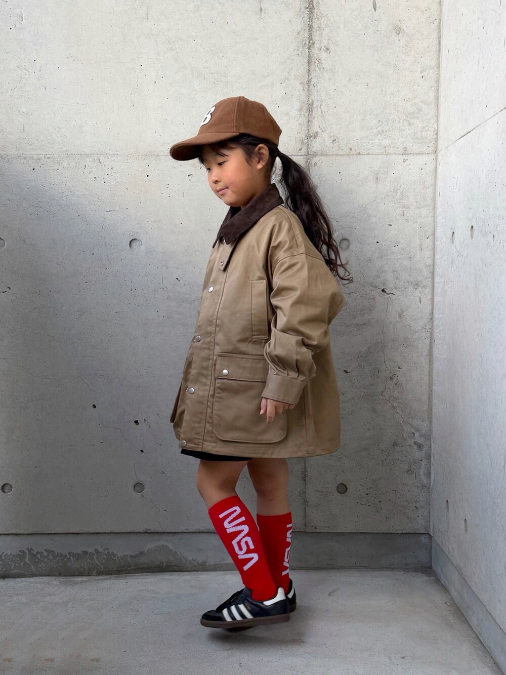ブラック系のスニーカー、ホワイト系のTシャツ/カットソー、ベージュ系のミリタリージャケットを着用したキッズの秋コーディネートの2枚目の写真