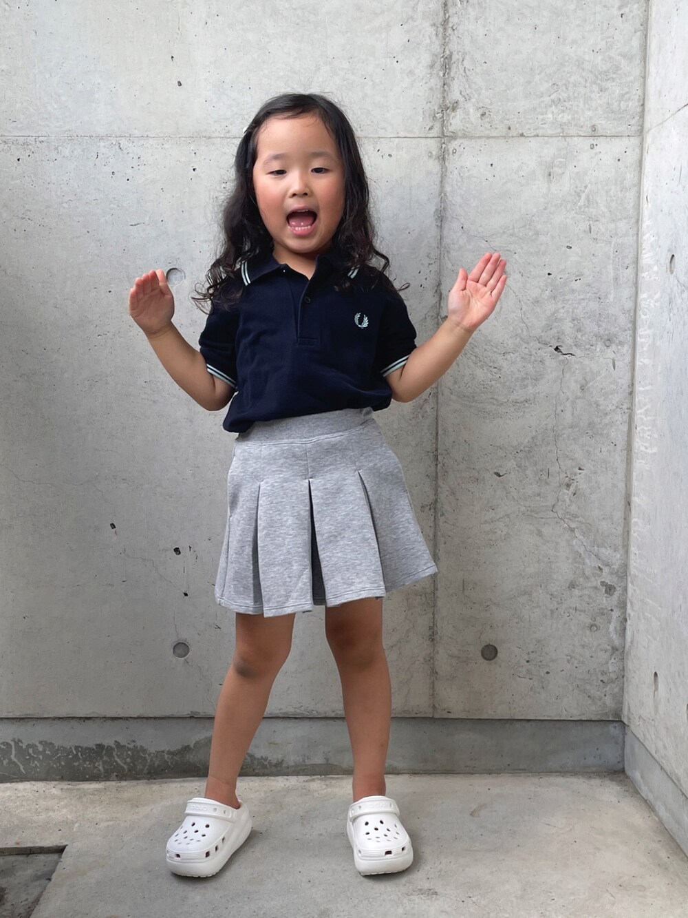 ホワイト系のサンダル、ブルー系のポロシャツ、グレー系のスカートを着用したキッズの夏コーディネートの3枚目の写真