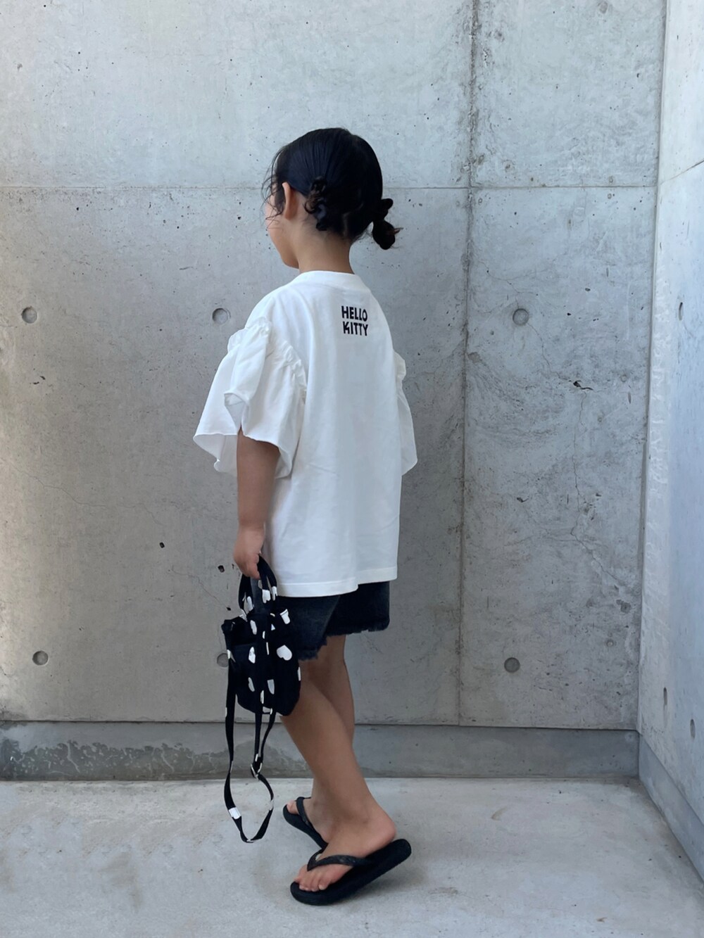 ブラック系のデニムパンツ、ブラック系のサンダル、ブラック系のショルダーバッグを着用したキッズの夏コーディネートの2枚目の写真