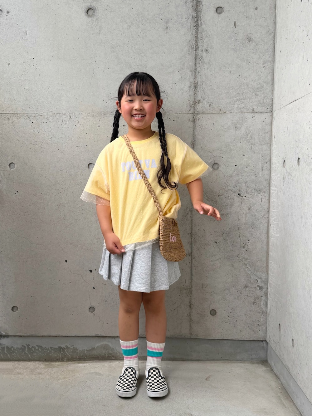 イエロー系のTシャツ/カットソー、ブラック系のスリッポン、グレー系のスカートを着用したキッズの春コーディネートの5枚目の写真