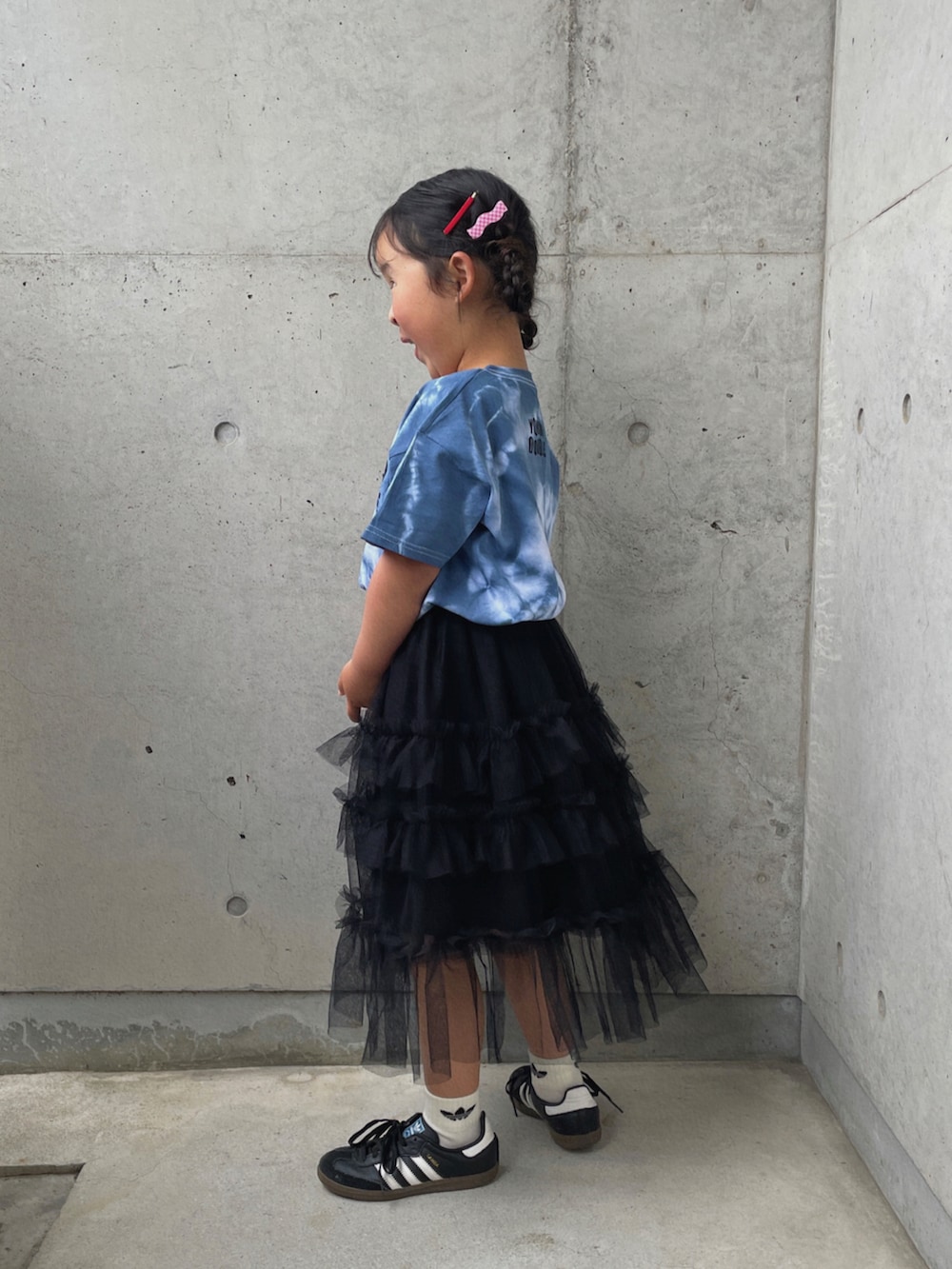 ブラック系のスカート、ブラック系のスニーカー、ブルー系のTシャツ/カットソーを着用したキッズの春コーディネートの2枚目の写真