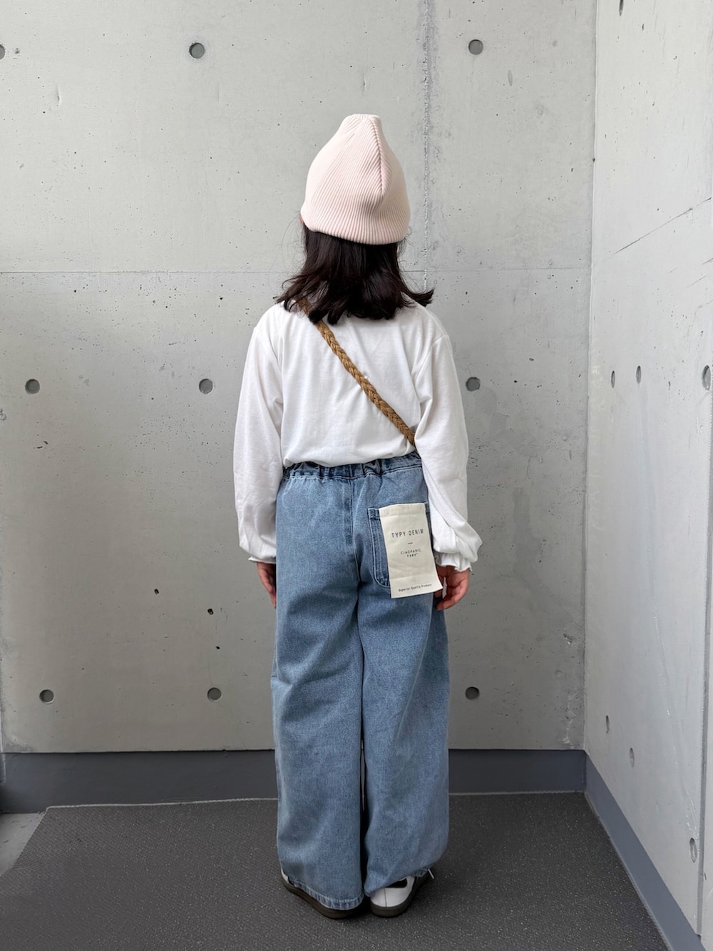 ベージュ系のショルダーバッグ、ホワイト系のTシャツ/カットソー、ブルー系のデニムパンツを着用したキッズの秋コーディネートの3枚目の写真