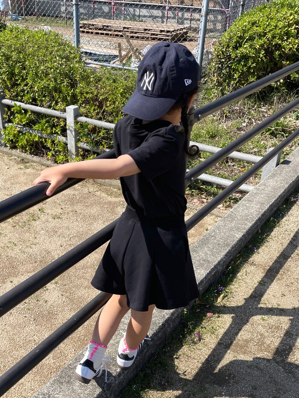 ブラック系のワンピース、ブラック系のスカート、ホワイト系のスニーカーを着用したキッズの春コーディネートの4枚目の写真
