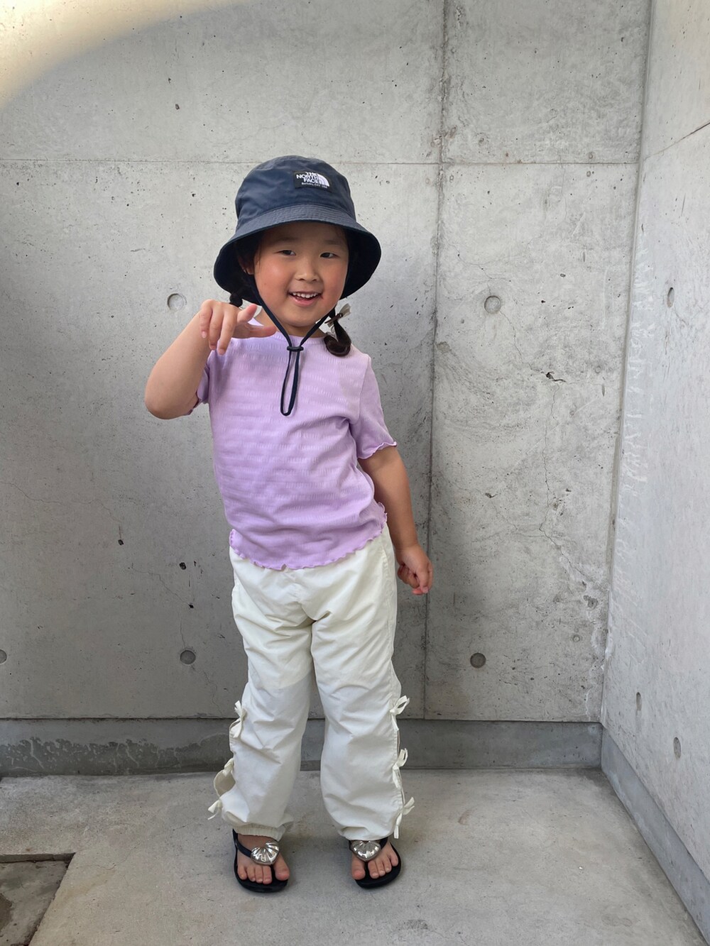 パープル系のTシャツ/カットソー、ホワイト系のその他パンツ、ブラック系のサンダルを着用したキッズの春コーディネートの2枚目の写真