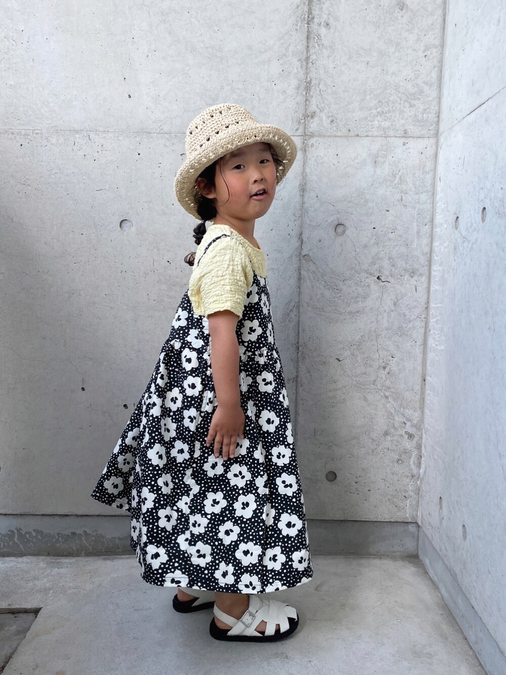 ブラック系のワンピース、ホワイト系のサンダル、ベージュ系のTシャツ/カットソーを着用したキッズの春コーディネートの4枚目の写真