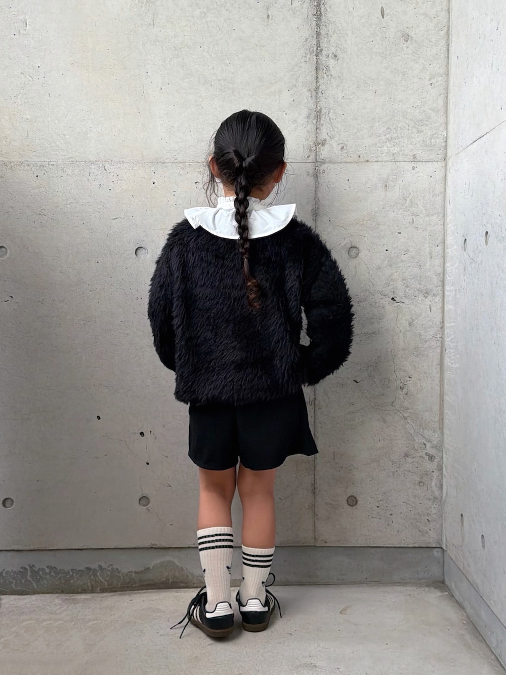 ブラック系のニット/セーター、ブラック系のスニーカー、ホワイト系のシャツ/ブラウスを着用したキッズの秋コーディネートの4枚目の写真