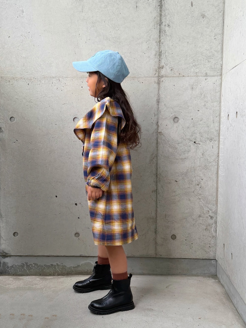 イエロー系のワンピース、ブラウン系のショルダーバッグ、ブラック系のブーツを着用したキッズの秋コーディネートの5枚目の写真