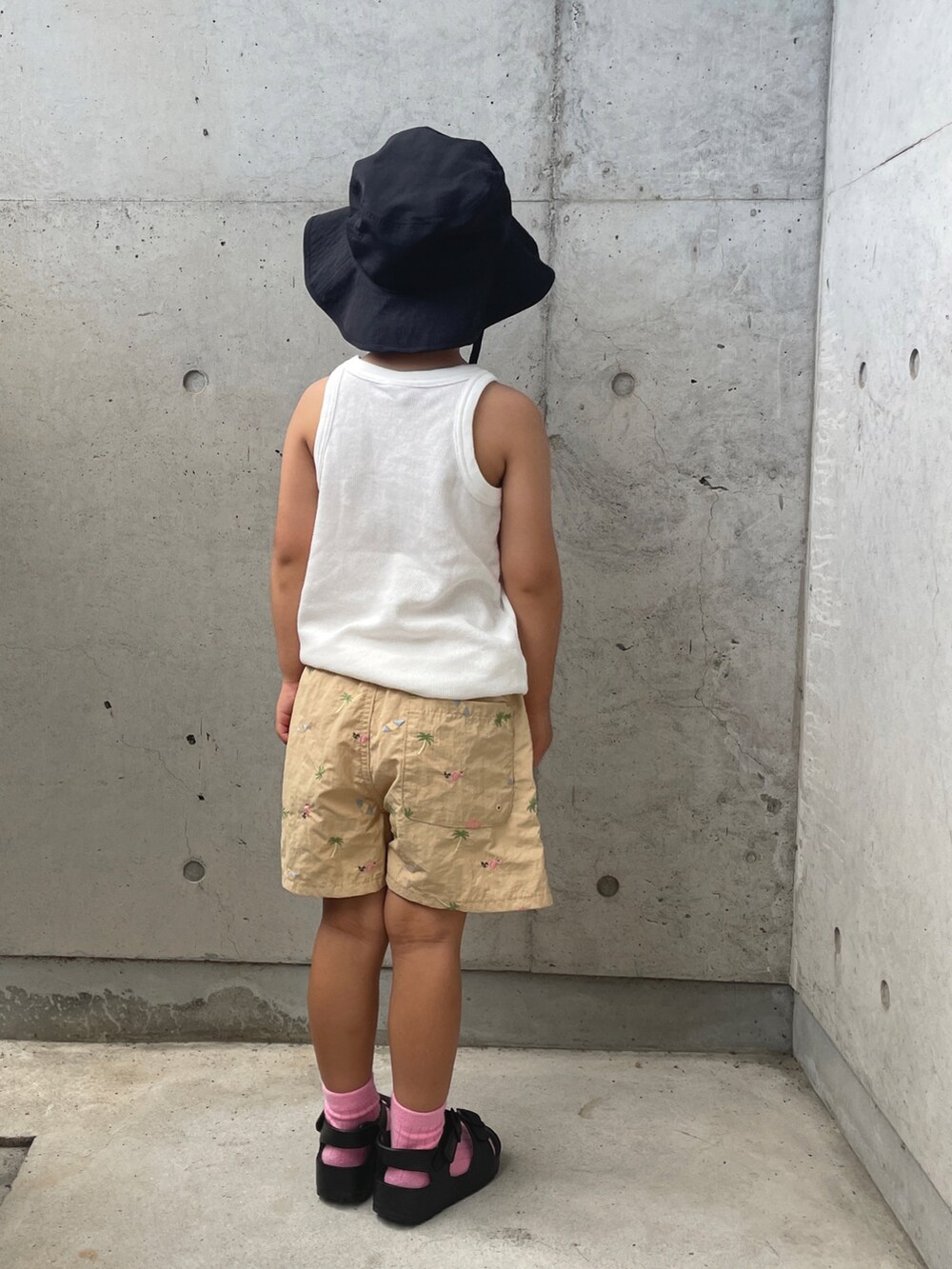 ホワイト系のタンクトップ、ベージュ系のパンツ、ブラック系のサンダルを着用したキッズの夏コーディネートの3枚目の写真