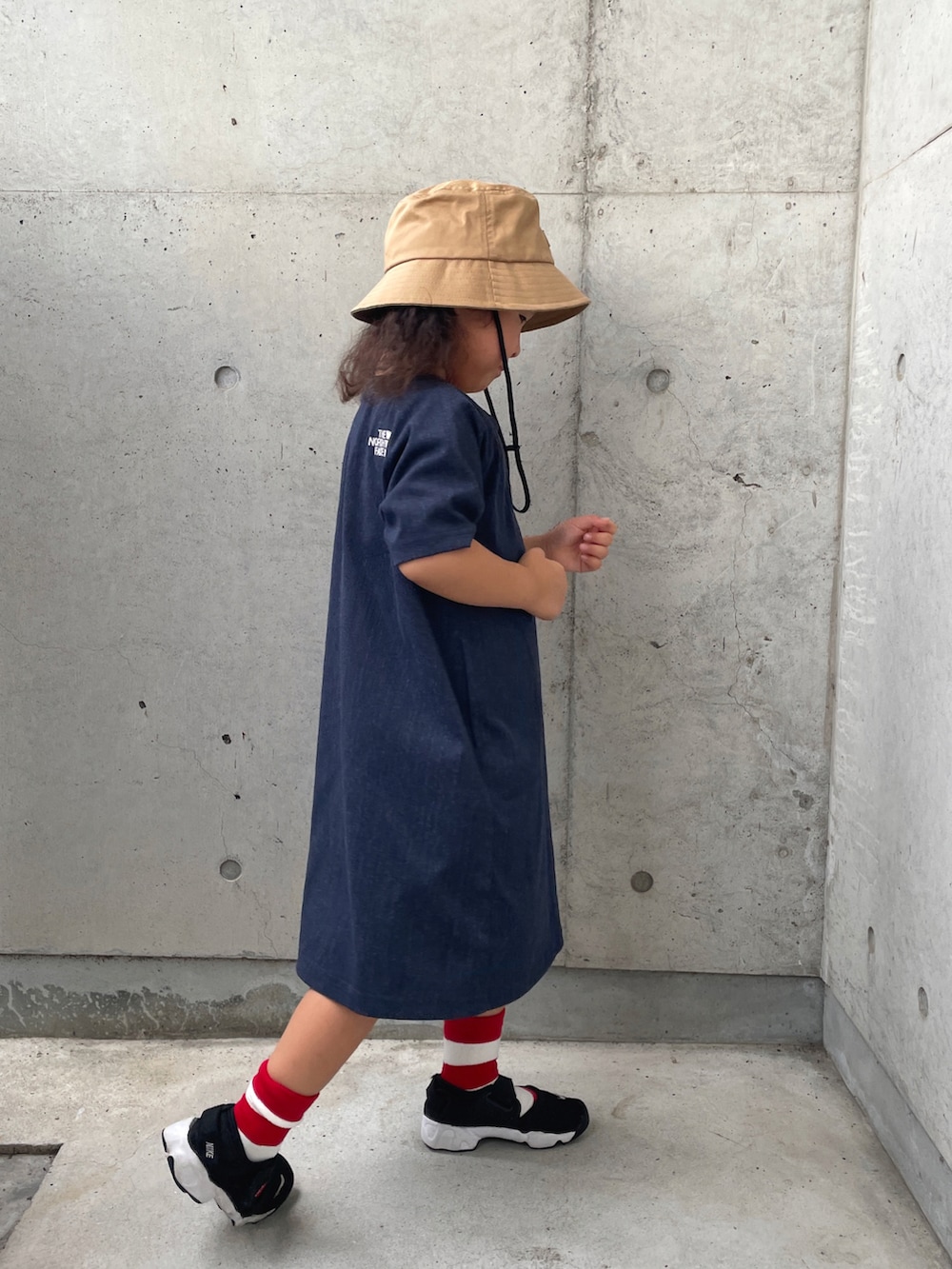 ブラック系のサンダル、ブルー系のワンピース、ベージュ系のハットを着用したキッズの夏コーディネートの3枚目の写真