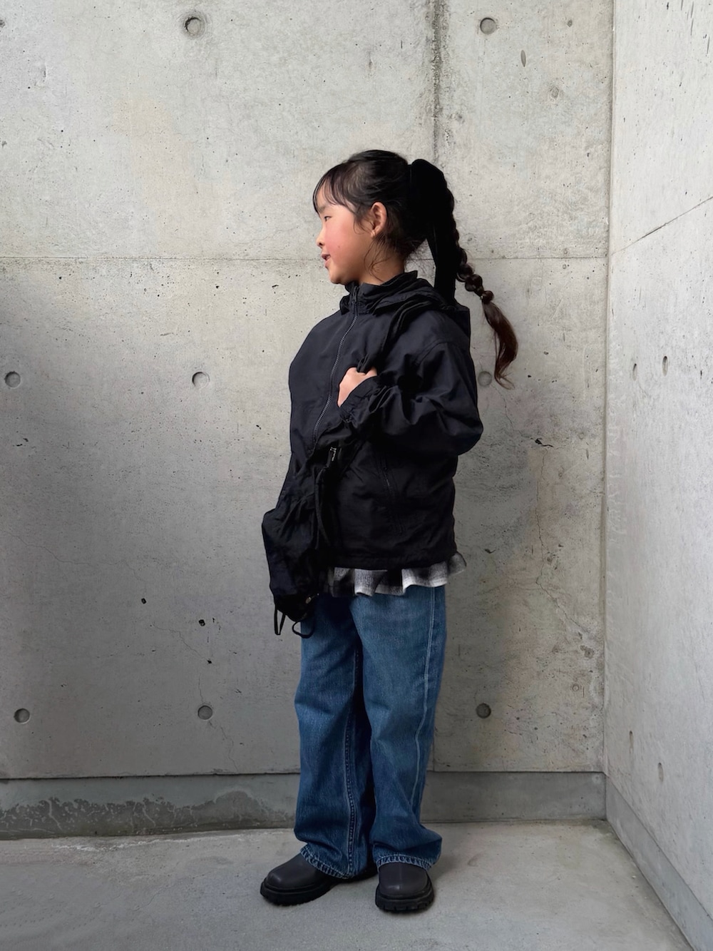 ブラック系のスカート、グレー系のブーツ、ブラック系のマウンテンパーカーを着用したキッズの春コーディネートの2枚目の写真