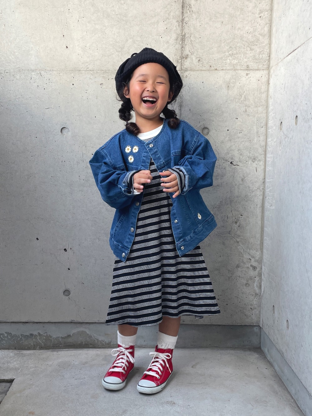 ブルー系のデニムジャケット、ブラック系のワンピース、レッド系のスニーカーを着用したキッズの秋コーディネートの2枚目の写真