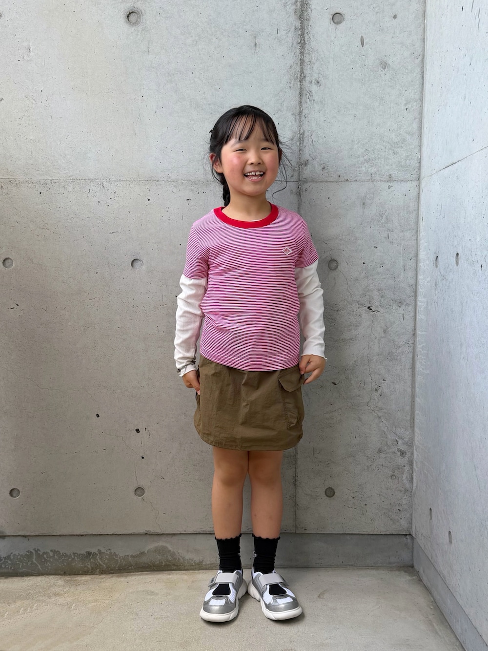 レッド系のTシャツ/カットソー、グリーン系のスカート、ホワイト系のバッグを着用したキッズの春コーディネートの3枚目の写真