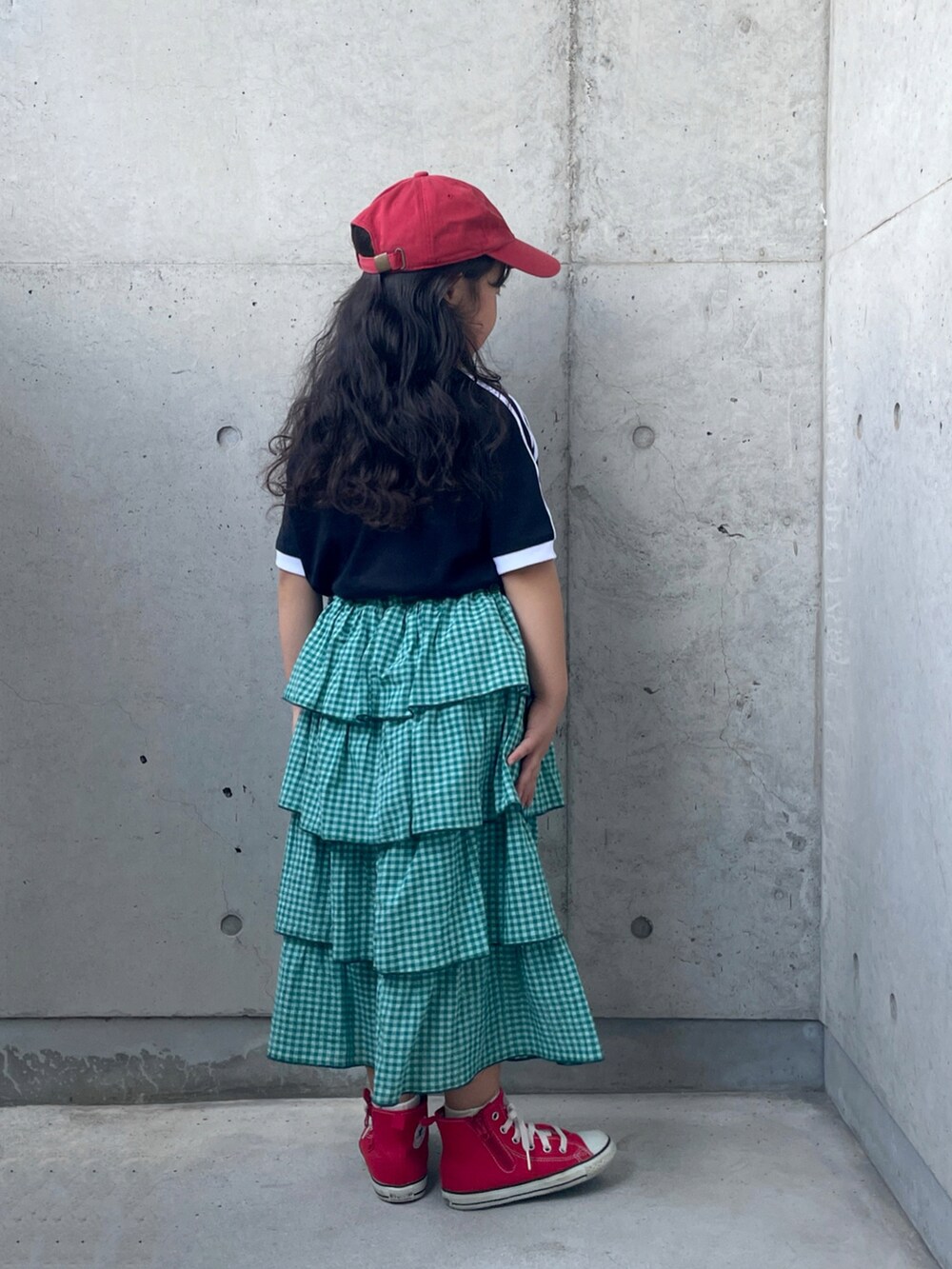 ブラック系のTシャツ/カットソー、レッド系のスニーカー、グリーン系のスカートを着用したキッズの秋コーディネートの3枚目の写真
