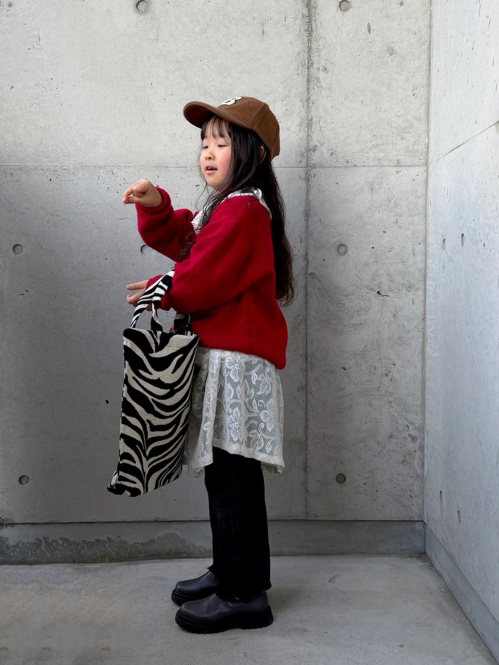 ベージュ系のスウェット、グレー系のブーツ、レッド系のニット/セーターを着用したキッズの冬コーディネートの2枚目の写真