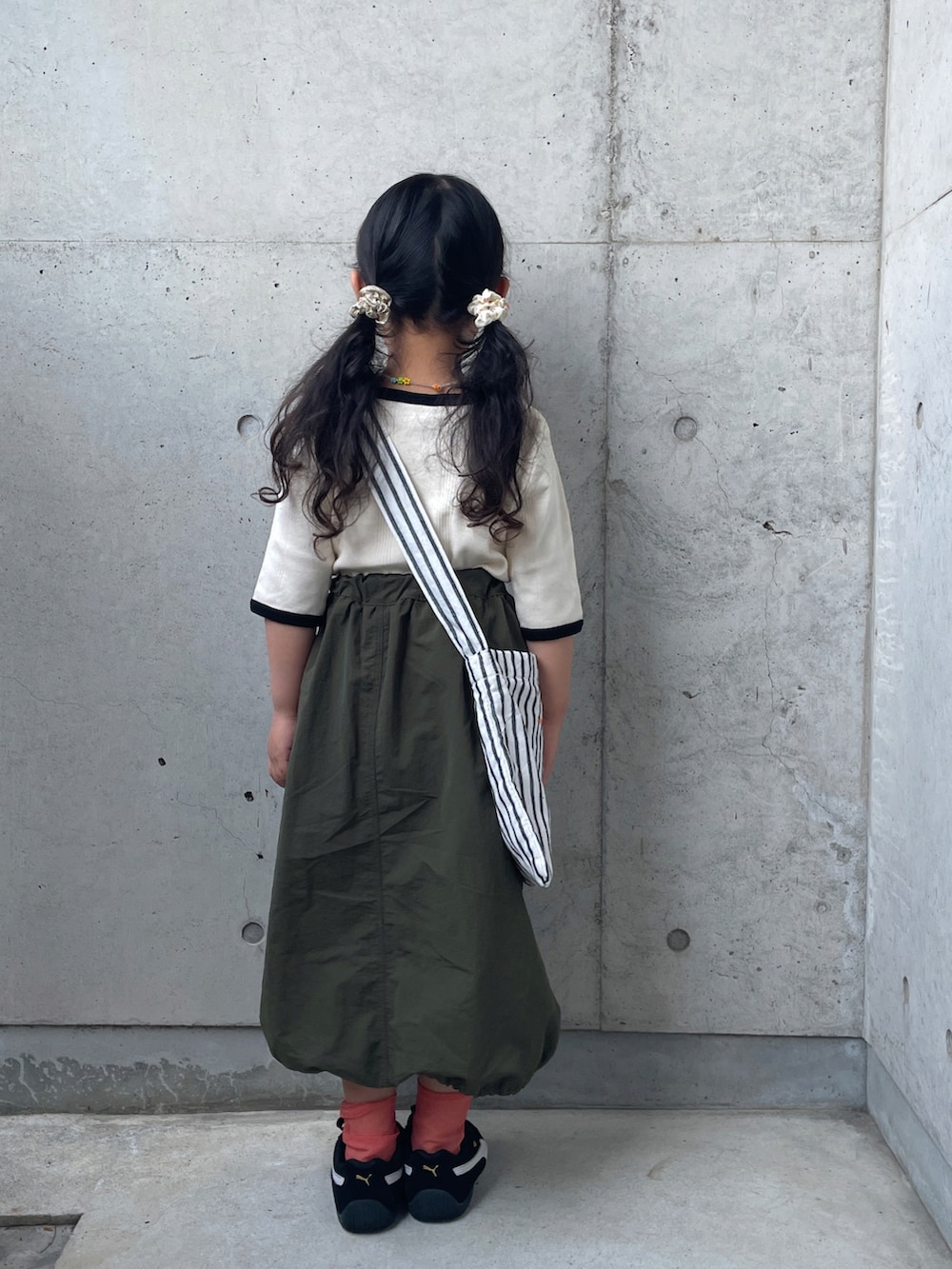 ホワイト系のTシャツ/カットソー、グリーン系のスカート、ブラック系のスニーカーを着用したキッズの春コーディネートの4枚目の写真