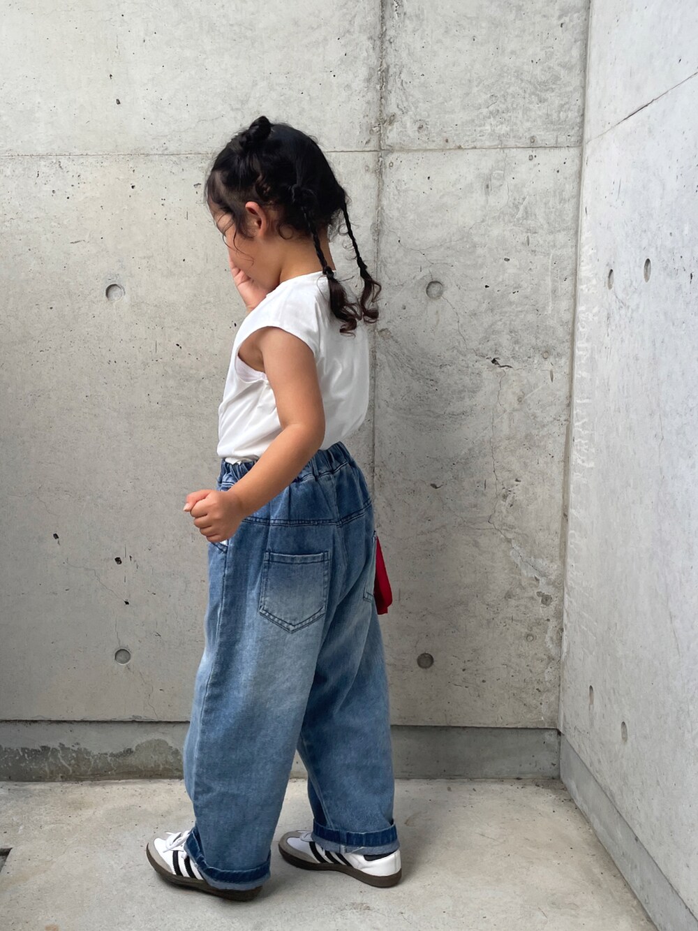 ブラック系のワンピース、ブルー系のデニムパンツ、ホワイト系のスニーカーを着用したキッズの夏コーディネートの5枚目の写真
