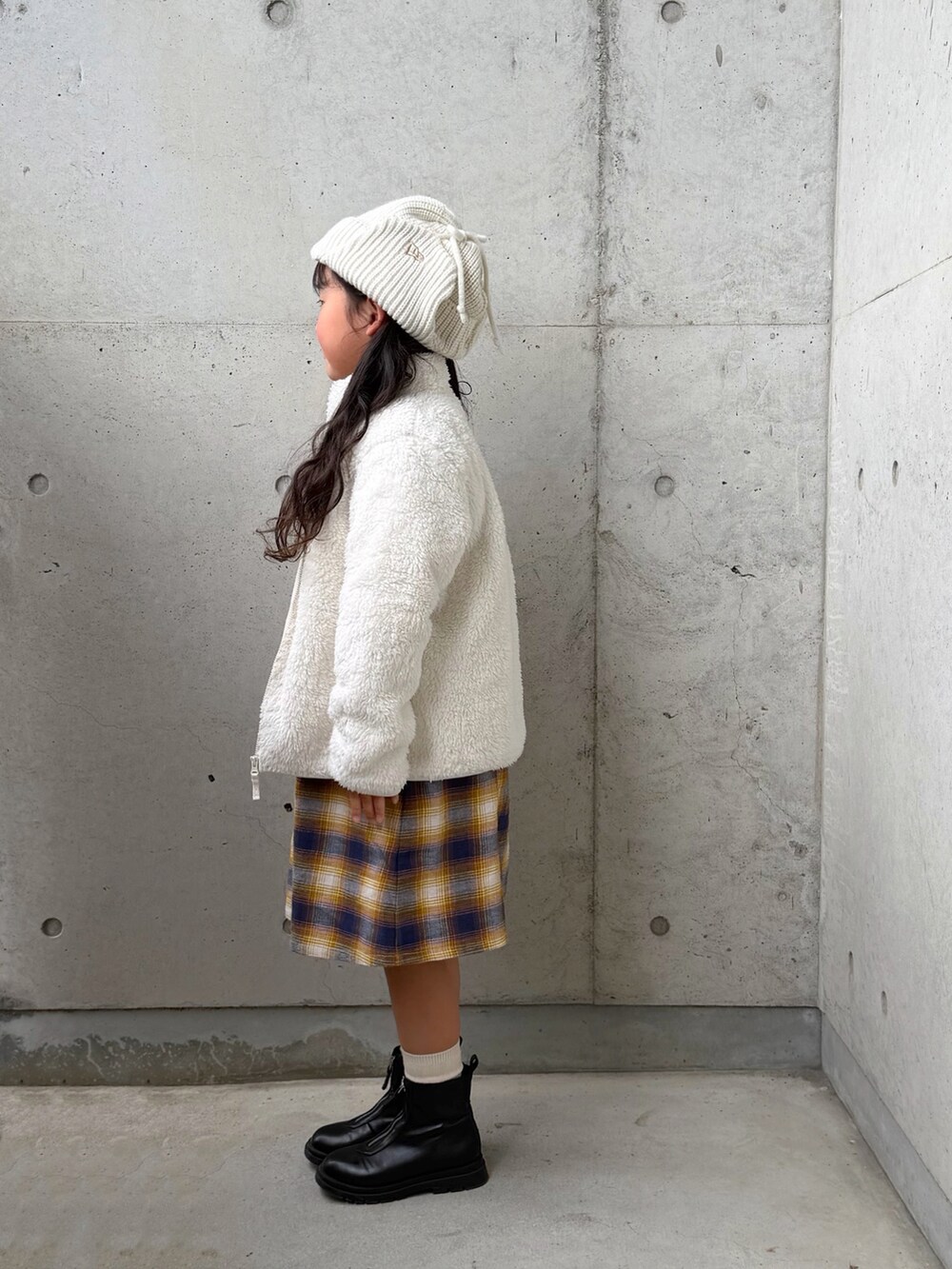 ブラック系のブーツ、ホワイト系のジャケット/アウター、イエロー系のワンピースを着用したキッズの秋コーディネートの2枚目の写真