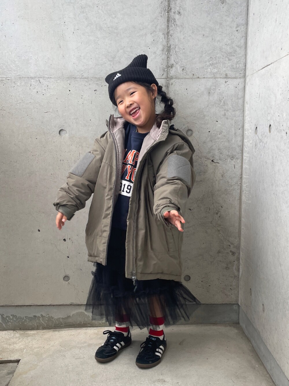 グリーン系のブルゾン、ブラック系のスカート、ブラック系のスニーカーを着用したキッズの冬コーディネートの3枚目の写真