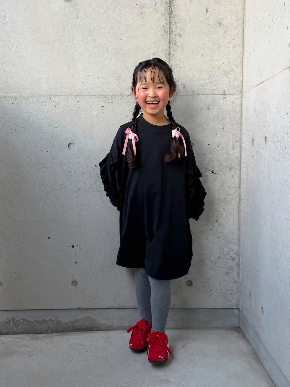 ブラック系のワンピース、レッド系のスニーカー、ピンク系のトートバッグを着用したキッズの春コーディネートの4枚目の写真
