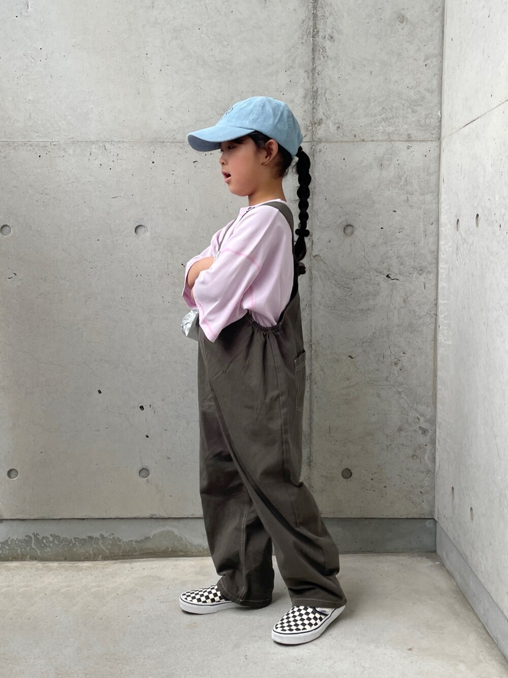 グレー系のサロペット/オーバーオール、ブラック系のスリッポン、パープル系のTシャツ/カットソーを着用したキッズの秋コーディネートの2枚目の写真