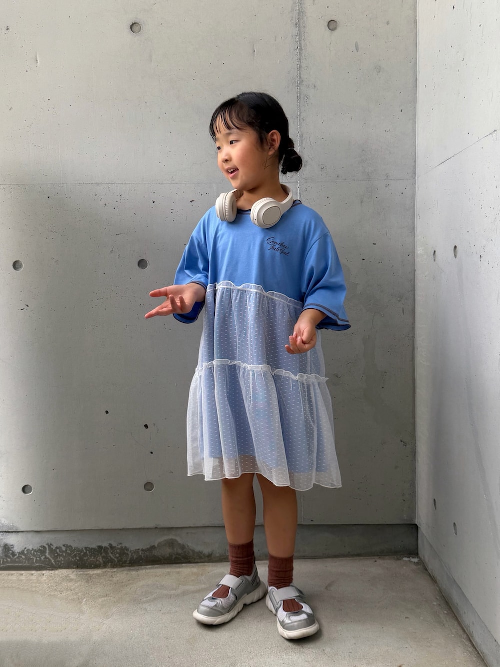 ブルー系のワンピース、シルバー系のスニーカー、ベージュ系のヘッドフォン/イヤホンを着用したキッズの夏コーディネートの2枚目の写真