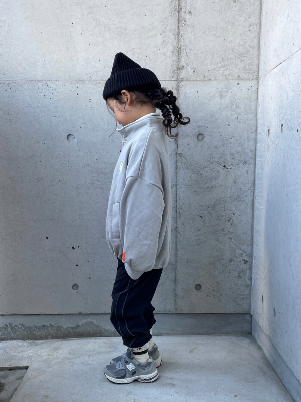 ブラック系のパンツ、ホワイト系のトップス、グレー系のスウェットを着用したキッズの冬コーディネートの2枚目の写真