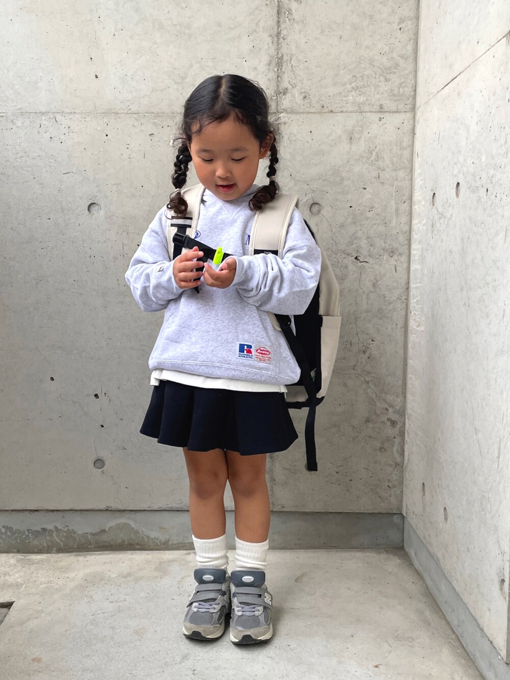 グレー系のスウェット、ホワイト系のTシャツ/カットソー、ブラック系のスカートを着用したキッズの秋コーディネートの3枚目の写真