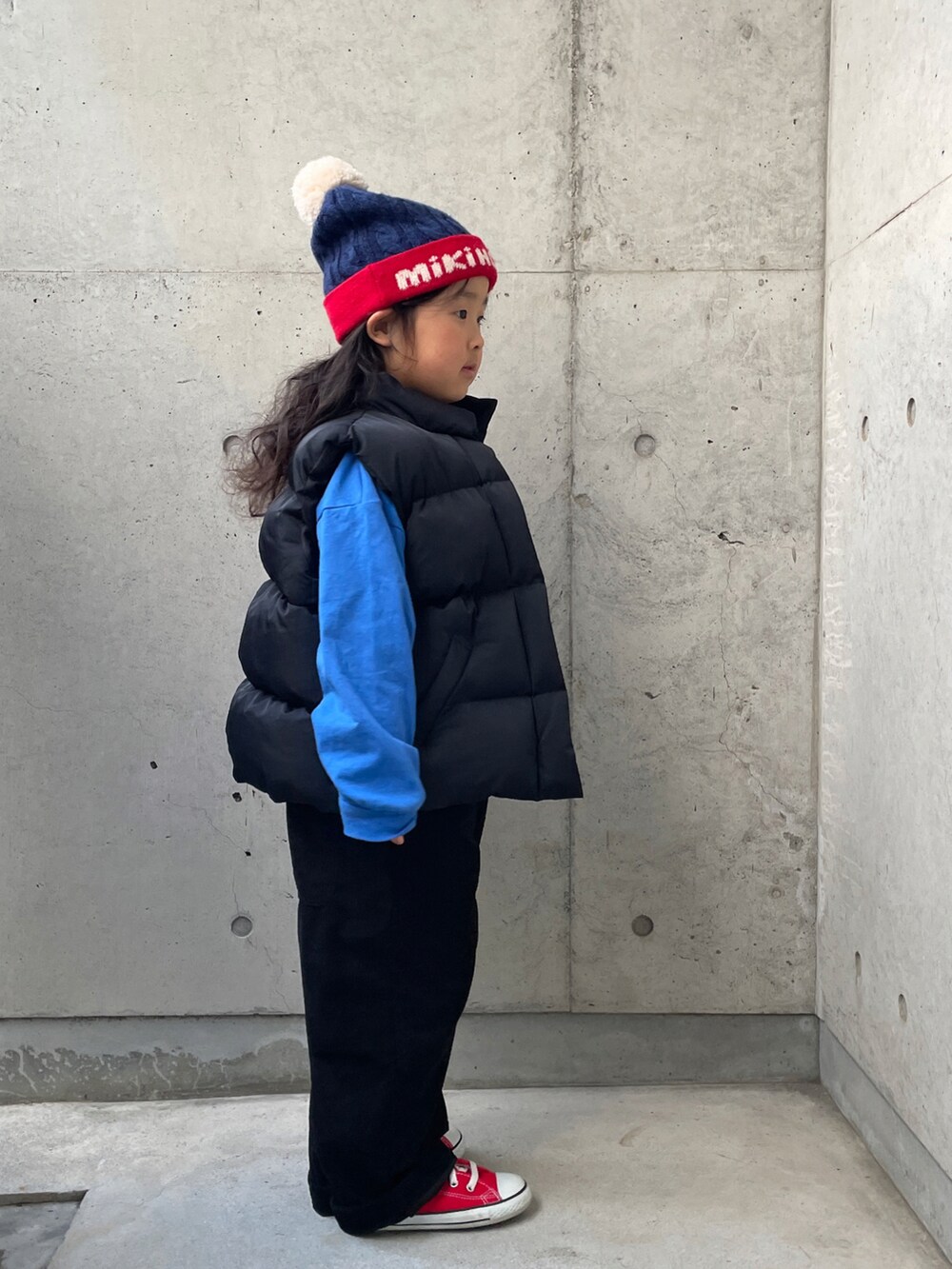 ブラック系のダウンベスト、ブルー系のTシャツ/カットソー、ブラック系のサロペット/オーバーオールを着用したキッズの冬コーディネートの2枚目の写真
