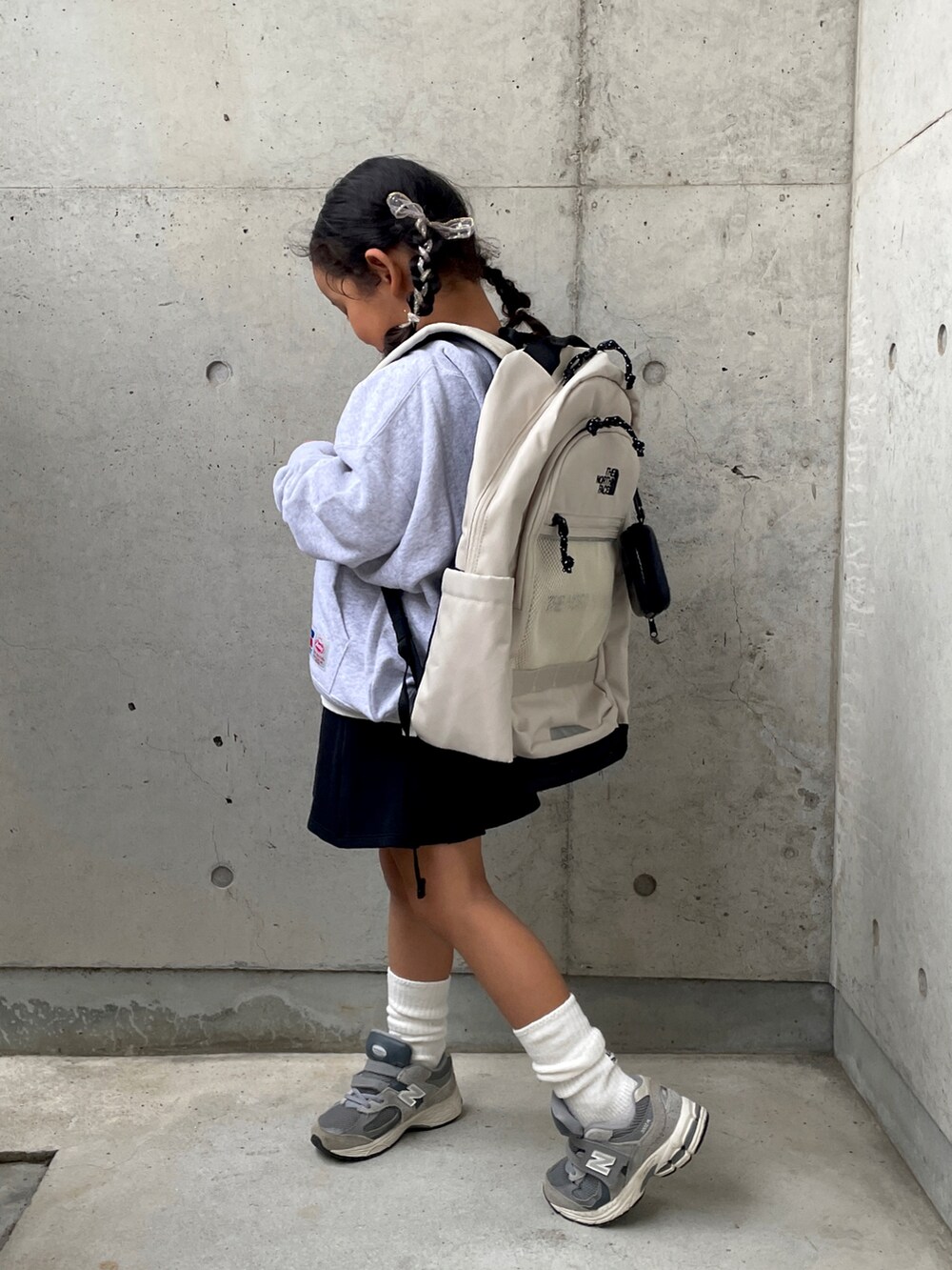 グレー系のスウェット、ホワイト系のTシャツ/カットソー、ブラック系のスカートを着用したキッズの秋コーディネートの4枚目の写真